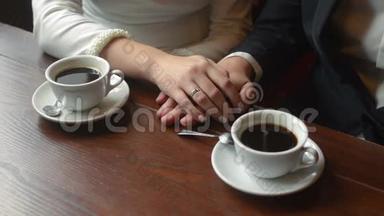 一对新婚夫妇在咖啡馆里牵手。 关门