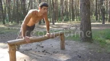在森林里做俯卧撑的运动员。 强壮的年轻肌肉男夏季在森林户外训练