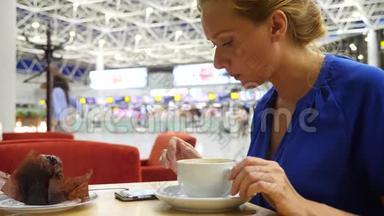 女士在<strong>机场</strong>候机室使用智能手机。 她喝咖啡。 对<strong>机场飞行</strong>的期望。 4k，慢动作