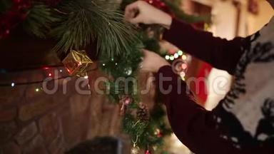 穿着针织毛衣的人把圣诞花环挂在石头上，用五颜六色的闪光花环装饰着真正的壁炉