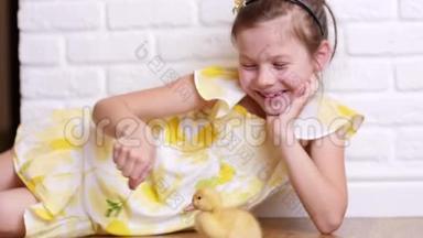 一个穿着黄色裙子的小可爱女孩正在和三只黄色的小鸭子玩，用草药喂它们。 小鸭子