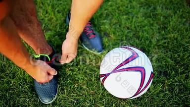 职业足球运动员练习在靴子上系鞋带. 用球特写..