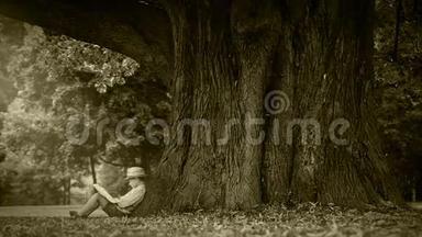 老电影效果片段：小男孩<strong>坐在树下</strong>看书