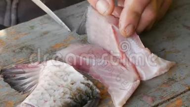 一个渔夫把一条活泼的大鱼切成碎片。 清洗淡水鱼以作进一步烹饪