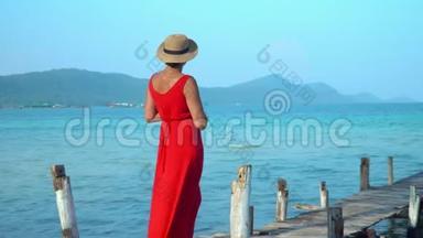 穿着红色长裙的女人.. 这位穿红色衣服的年轻女子在码头上花钱，远远地看着。 女人在码头上花钱