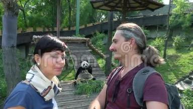 两个快乐的人在动物园里看熊猫