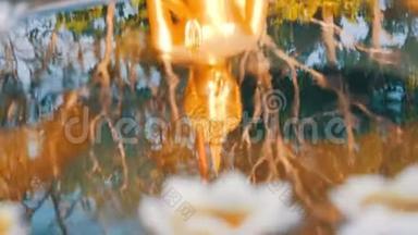 美丽的<strong>金色</strong>倒影在水中的<strong>佛像</strong>上，各种蜡烛以莲花的形式漂浮着