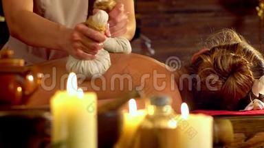 年轻女子在水疗沙龙用燃烧的蜡烛进行热敷按摩。