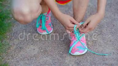 年轻女子的双手系着明亮的粉红色和蓝色<strong>运动鞋</strong>。 <strong>跑鞋</strong>-女人系鞋带的特写。