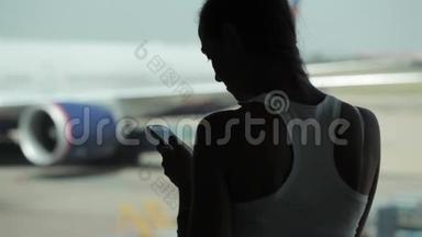年轻女子<strong>在机场</strong>用智能手机吃零食