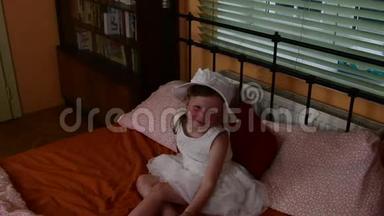 一个可爱的小女孩坐在床上微笑。 父母卧室和女儿在床上。 一个小女孩