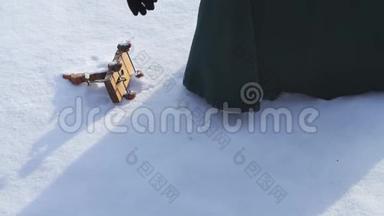孩子们`玩具躺在雪地里，女人拿着它。 小雪人玩具在雪中。 手拿圣诞玩具复古风