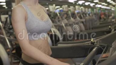适合在现代健身房跑步机上跑步的女人。 健康的年轻女孩在健身房运动跑步机