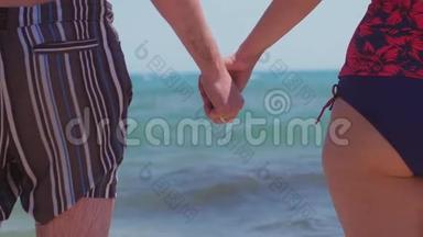 一对夫妇在海滩上的<strong>大海</strong>背景上牵手。 双手紧贴<strong>大海</strong>。 慢动作