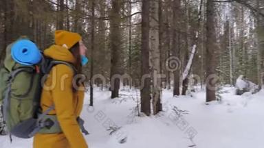 女<strong>游客</strong>走在冬天的<strong>森林</strong>小路上，肩上背着一个背包。