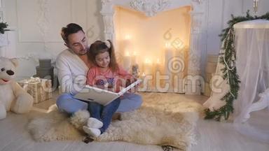 平安夜，年轻的父亲和女儿坐在壁炉前<strong>讲故事</strong>