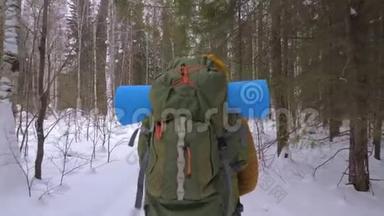 女游客走在冬天的森林小路上，肩上背着一个背包。