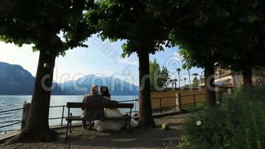 新婚夫妇在意大利科莫湖的长凳上接吻