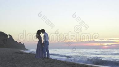 迷人的深爱的年轻夫妇晚上在海滩上有一个甜蜜的浪漫时刻。 浪漫蜜月概念