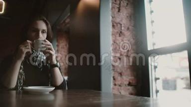 在loft cafe 4k，一个女人用她的智能手表触摸屏喝着咖啡看着窗外
