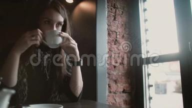 在loft cafe 4k，一个女人用她的智能手表触摸屏喝着咖啡看着窗外