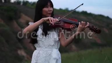 黄昏时分，亚洲女子<strong>小提琴</strong>手在草地上拉<strong>小提琴</strong>。