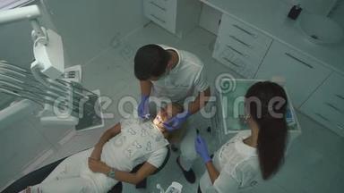 程序中的牙医。 牙科专家检查病人的口腔健康，当助理给予