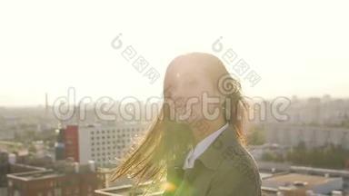 日落时站在屋顶上的年轻女子转过头，头发看着相机。 慢节奏