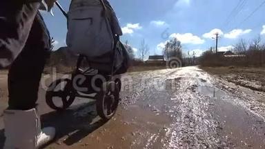 女孩在泥泞的乡间小路上推着婴儿车散步，高清视频