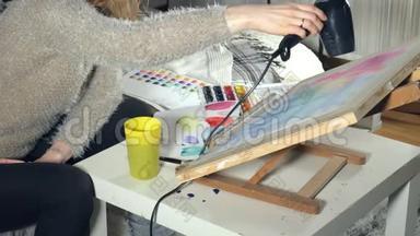 成年妇女用彩色水彩颜料作画，在<strong>艺术学校</strong>用吹风机吹干