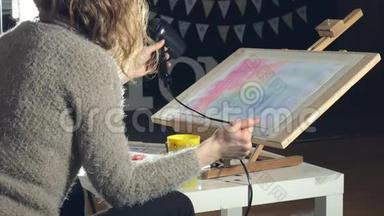 成年妇女用彩色水彩颜料作画，在艺术学校用吹风机吹干