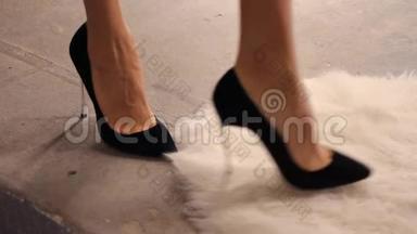 年轻女子在鞋店里穿高跟鞋。 一个女人试穿黑色绒面高高跟鞋。 脚踩在上面