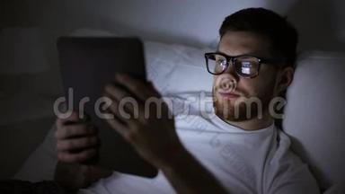 带眼镜和平板电脑<strong>的男人</strong>晚<strong>上躺在床上</strong>