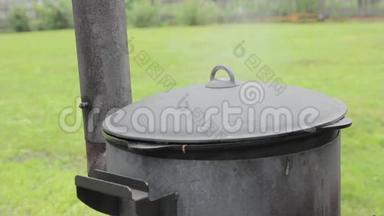 在外面的大锅里用木炉做饭，锅盖下面蒸
