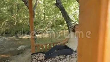 躺在树林中凉亭地毯上的年轻女子