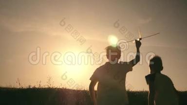 两个男孩在日落时玩一架木飞机。 <strong>儿童</strong>玩飞机的剪影。 飞行的<strong>梦想</strong>。 概念