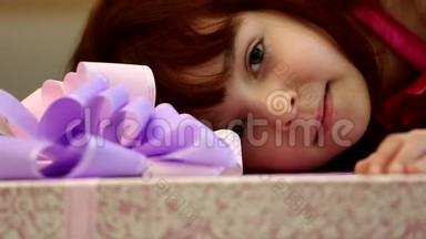 小可爱快乐的女孩孩子看起来拿着一个巨大的礼物盒，包裹着紫色的丝带蝴蝶结。