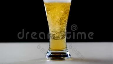 啤酒在黑色背景下倒入玻璃中。 啤酒杯中的气泡和泡沫.. 泡沫滑下啤酒杯