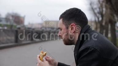 成年男子在城市里的长椅上吃热狗
