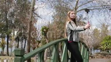 年轻快乐的女人用智能<strong>手机手机</strong>相机在木桥上<strong>拍摄</strong>自己的肖像。 特写