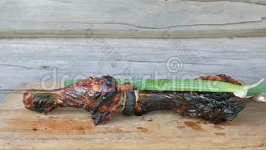 烤肉中的熟肉放在一块有洋葱的木板上。 粗糙，轻微烧焦的碎片.. 木制墙上