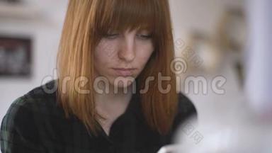 年轻漂亮的红发女郎在家里使用智能手机