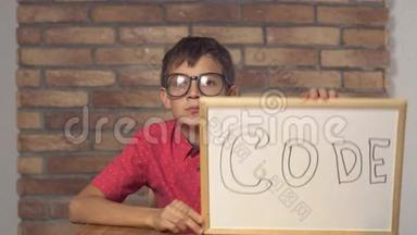 坐在书桌前的孩子拿着一张挂图，上面有红色砖墙上的字母代码