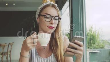 年轻女孩在手机上发短信。 女人在咖啡馆的智能手机上使用messanger，微笑着。