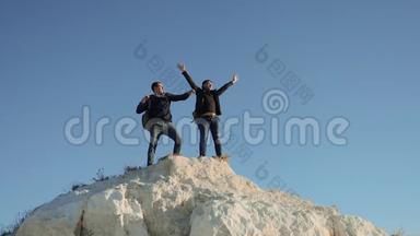 两个男子游客徒步探险登山者登山成功手把自由举起。 慢动作视频。 hike