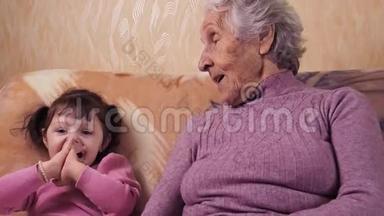 奶奶和孙女玩。 奶奶和孙女在家里的沙发上玩得很开心。