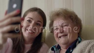 奶奶和年轻女孩在家里坐在<strong>沙发</strong>或<strong>沙发</strong>上用<strong>手机</strong>或智能<strong>手机</strong>拍照。 快乐的女士们