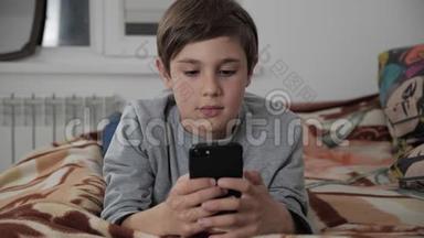 小孩在家玩手机。 小孩用智能手机躺在床上