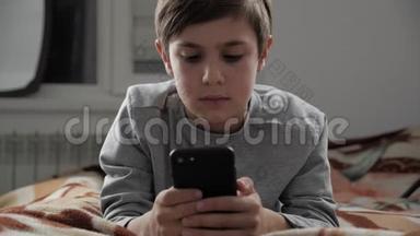小孩在家玩手机。 小孩躺在床上使用智能手机