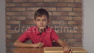 坐在办公桌前的孩子拿着一张挂图，背景上红砖墙上刻着字母的老板。